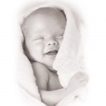 Smilende nyfødt baby svøbt i et tæppe