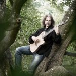 Mand spiller guitar i skoven